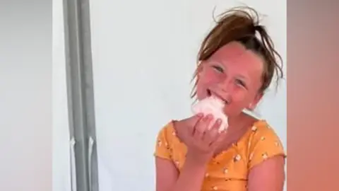 Family Handout A child eating candy floss and smiling.