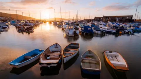 Getty Images A general view of Lyme Regis harbour in June, with the sun setting in the background 