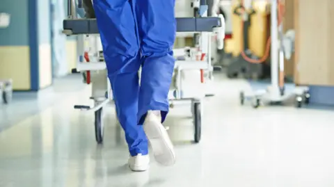 Getty Images Surgeon walking a hospital bed down a corridor