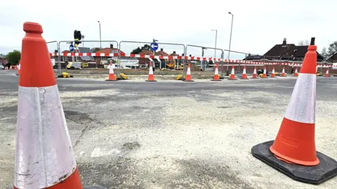 Paul Moseley/BBC Two red and white traffic cones are in the foreground. Behind them many more surround a fenced-off roundabout.