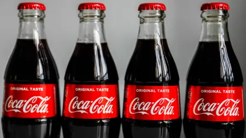 Getty Images Four Coca-Cola bottles standing side-by-side.
