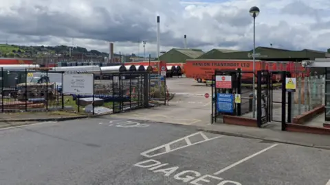 Google Maps A screengrab of a Google Maps view of Diageo's canning facility off Belfast's Castlereagh Road in 2019.  The industrial estate site consists of large green warehouses, fenced off behind a large black metal fence.  A number of silver-sided Guinness lorries are parked in the car park, along with several orange lorry trailers 