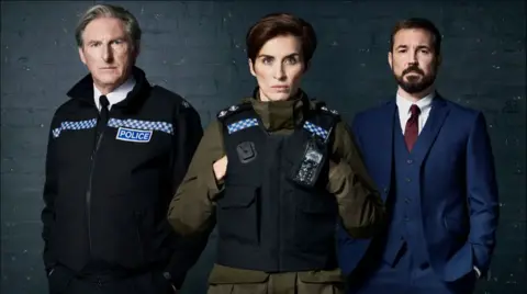 The actor appear in character in their standard attire - Dunbar and McClure in police uniform and Compston in a blue suit.