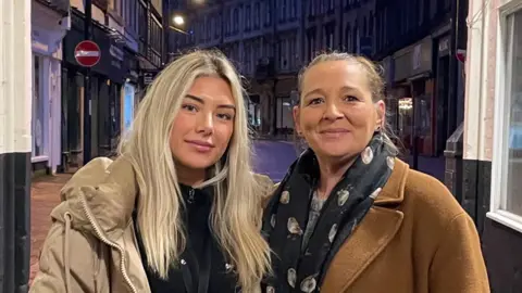 BBC Daisy and Emma and wearing warm jackets and standing at the entrance of a rough sleeping hotspot