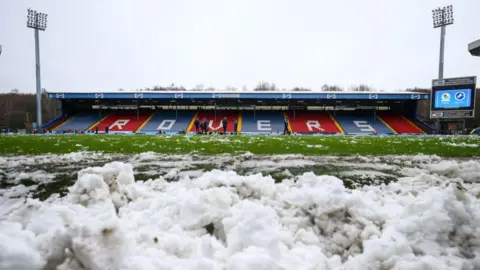 Getty Images Snow lies round the edges of the pitch at Blackburn Rovers' ground. The word "Rovers" is spelt out in white seats among the red and white blocks.