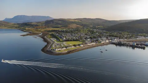 Getty Images Una vista aérea de Ullapool con el pueblo a orillas de Loch Broom. Un bote deja una estela en el lago.