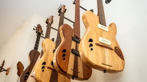 Matt Bigwood Finished electric guitars hanging on a wall