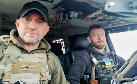 SHAUN PINNER A selfie of two men Shaun Pinner, and Chris Garrett in military style vests in a car
