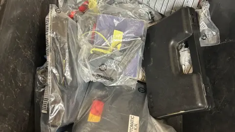 A blank firing pistol sits in an evidence bag in a box filled with other examples