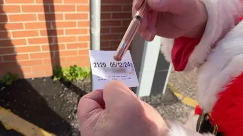 Father Christmas holding the parking ticket he bought