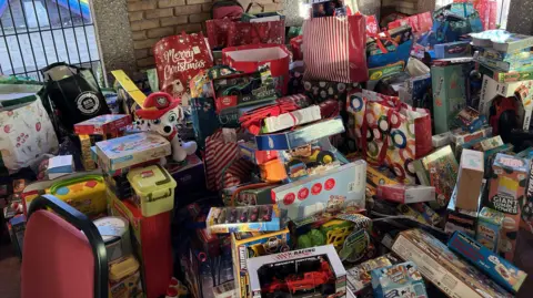 BBC/Antony Collins A large pile of assorted children's toys and games, stacked on top of each other.