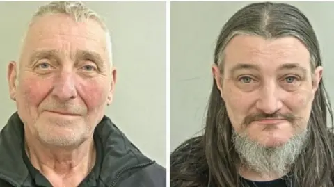 National Crime Agency Two mugshots side by side of two middle-aged men. The one on the left has short hair and stubble while the one on the right has long hair and a beard. 