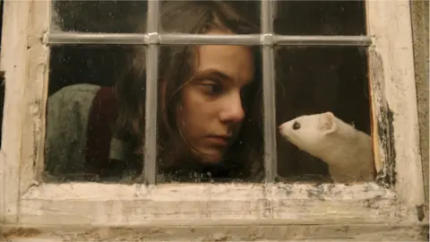 BBC | Bad Wolf | HBO Lyra (Dafne Keene) with her daemon Pantalaimon, seen here as an ermine