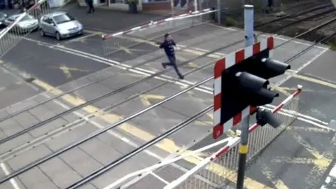 Network Rail Man running across level crossing