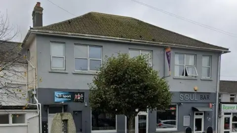 Google Google Street View image of Soul Bar in Camborne. The building is two shades of grey and has a tree outside the front door.