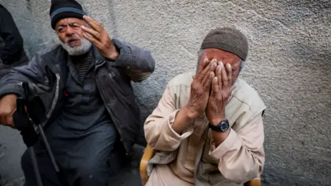 Reuters Two elderly Palestinian men react - one holds up his hand, the other holds his head in his hands - at the site of an Israeli strike on a building in Jabalia in northern Gaza