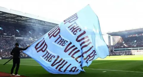 Reuters A shot of Aston Villa's stadium, with a man pitchside, with a large banner bearing the words Up The Villa