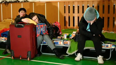 People rest at a refugee shelter in a school gym in the village of Ubla, Slovakia, in February 2022 after Russia launched its war against Ukraine