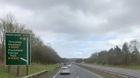 Google The A69. There is a green sign on the left, giving directions for Newcastle, Throckley, Newburn, Ponteland and Darras Hall. A grey and a white car are travelling in the left lane, with more vehicles further ahead. 