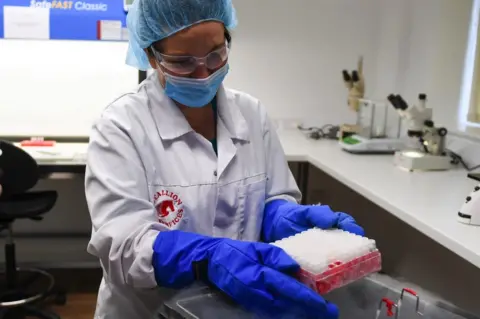 NAtures Safe A scientist holds tissue vials over a canister of liquid nitrogen