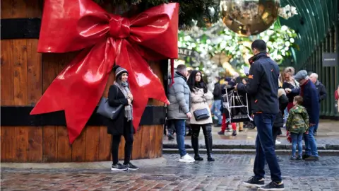 PA Media Woman posing next to Christmas decorations in London's Covent Garden