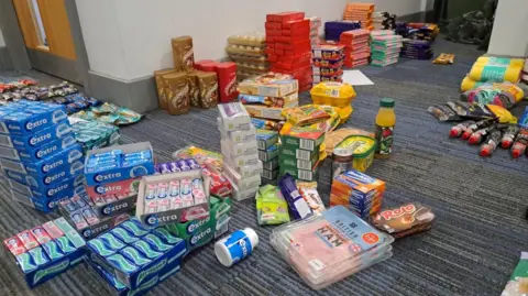 Cambs Police Lots of packets of chewing gum are lined up on a blue-grey carpet with other items including packets to ham and boxes of chocolates