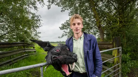 FremantleMedia Ltd/Naked West Charlie Cooper with a costume head of the Black Shuck, a ghostly dog that roams East Anglia 