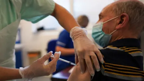 Getty Images Man being vaccinated at a GP surgery