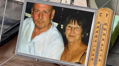 BBC News A snap of Mrs Hull and her late husband John beside a wooden thermometer which reads less than 10C. 