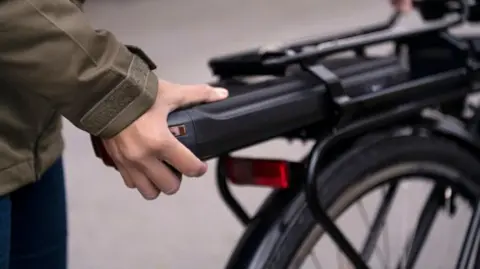 A generic stock shot of a man's hand - clicking in the battery for his e-bike.