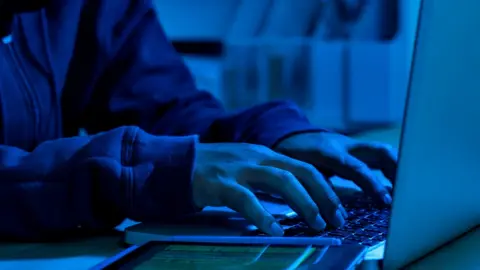 Getty Images Anonymous person on the computer in blue light