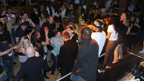 ESP Magazine A band performing on stage in front of a crowd of clubgoers.