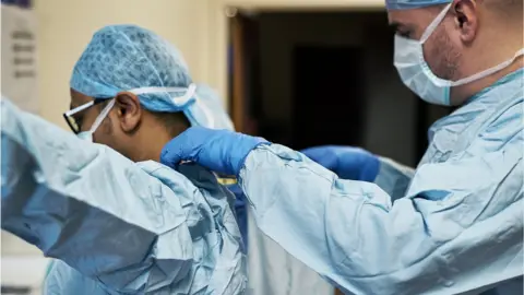 Getty Images Doctors putting on gowns