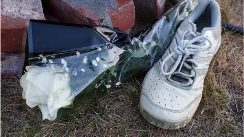 Getty Images A running shoe and white rose at a memorial