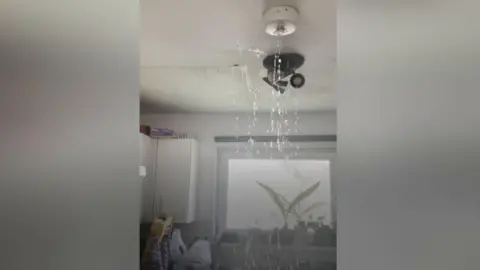 Water raining down from a light fixture into a kitchen