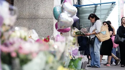 PA Media Flowers are left at the scene near to where Elianne Andam was killed