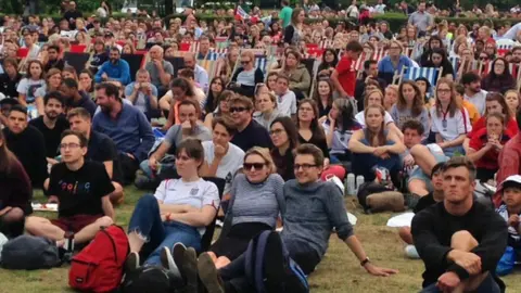 BBC A mass of England fans in Battersea Park, London., watching England