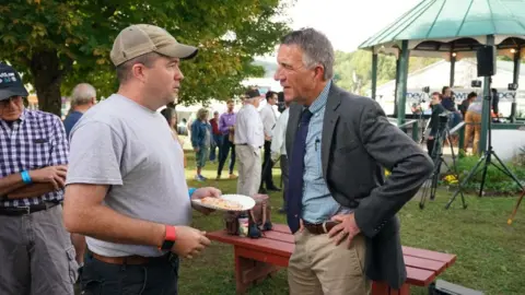 Getty Images Phil Scott (R) talks to a voter at a Vermont fair