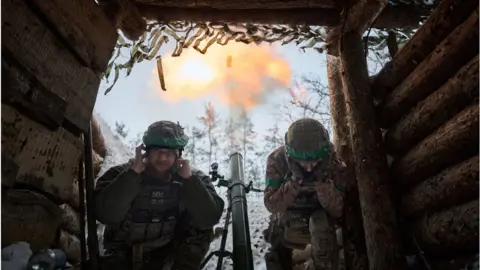 Getty Images Two Ukrainian soldiers duck after firing a mortar