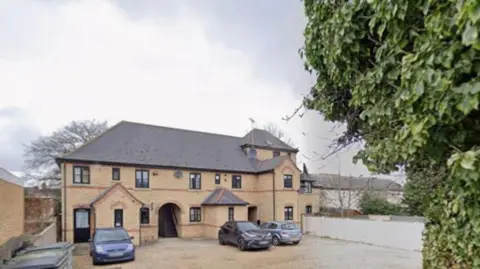 Google Henry Court is a modern redbrick building with an arched entrance and stairs leading to the upper floors. There are some cars parked at the front.