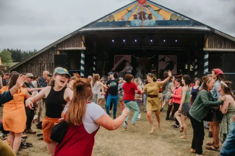 Recompose Revellers at the Knockengorroch Festival dancing around arm in arm