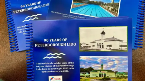 Friends of Peterborough Lido A blue hardbound book with pictures of the Lido on front of it.
