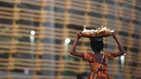 A woman carries a basket on her head