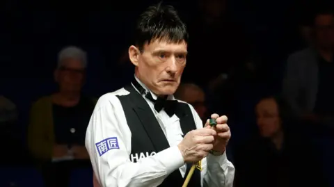 Jimmy White chalks his cue during his match against 
