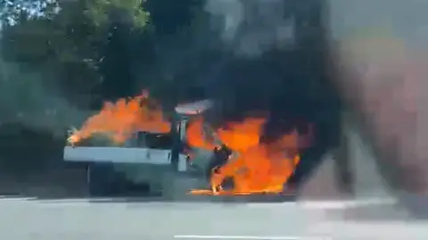 A truck in flames on the side of a motorway