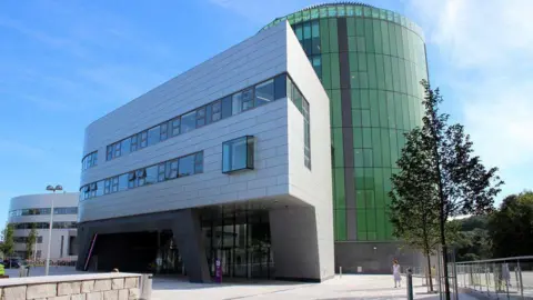 Robert Gordon University, buildings in Aberdeen, one mainly green glass, with trees and people visible.