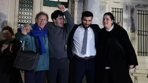 Sarah Mardini (R), Nasos Karakitsos (2nd R), Sean Binder (2nd L) and Pieter Wittenberg celebrate outside the courthouse 
