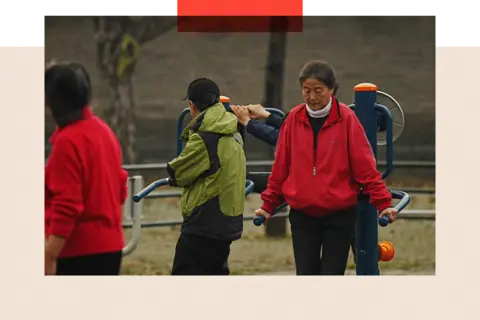 Getty Images A group of people on gym equipment exercise in the park