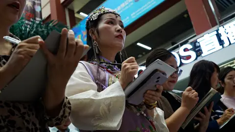 Xiqing Wang, Xiqing Wang Women stand in a line with notebooks and phones