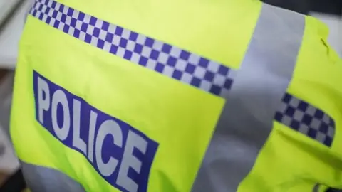 BBC A close up shot of a yellow high-vis jacket with the word police written on it.